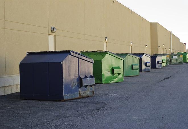 a construction worker unloading debris into a blue dumpster in Cutler